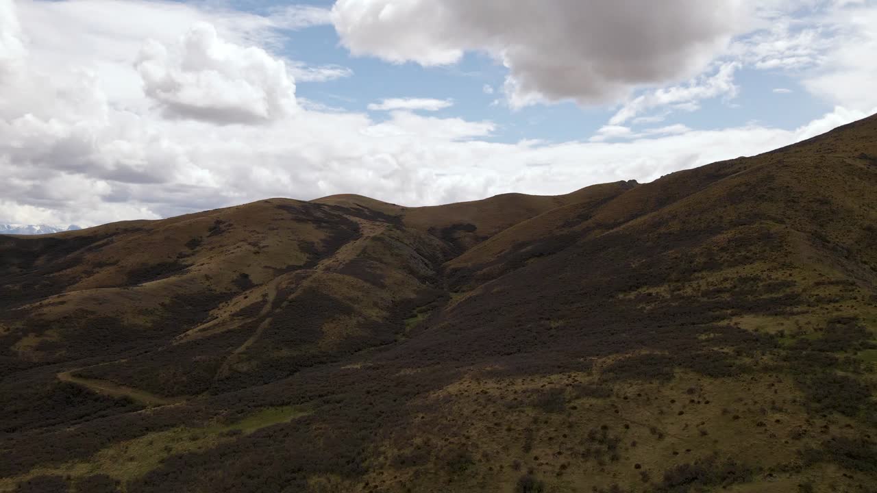 imágenes aéreas de un vuelo sobre colinas y llanuras para revelar una majestuosa cadena montañosa cubierta de nieve a lo lejos
