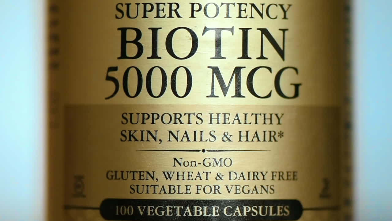 Inquadratura ravvicinata di un barattolo di pillole di biotina da 5000 mcg, vitamine B7. Rallentatore