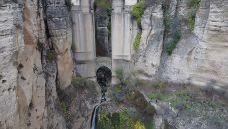 aerial descends height of historic arch bridge over deep chasm, spain