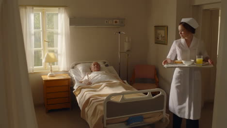 nurse serves breakfast to a patient in a hospital room