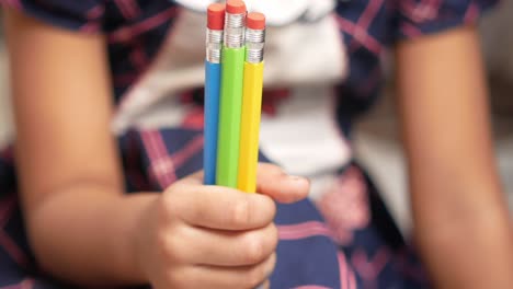 child holding colorful pencils