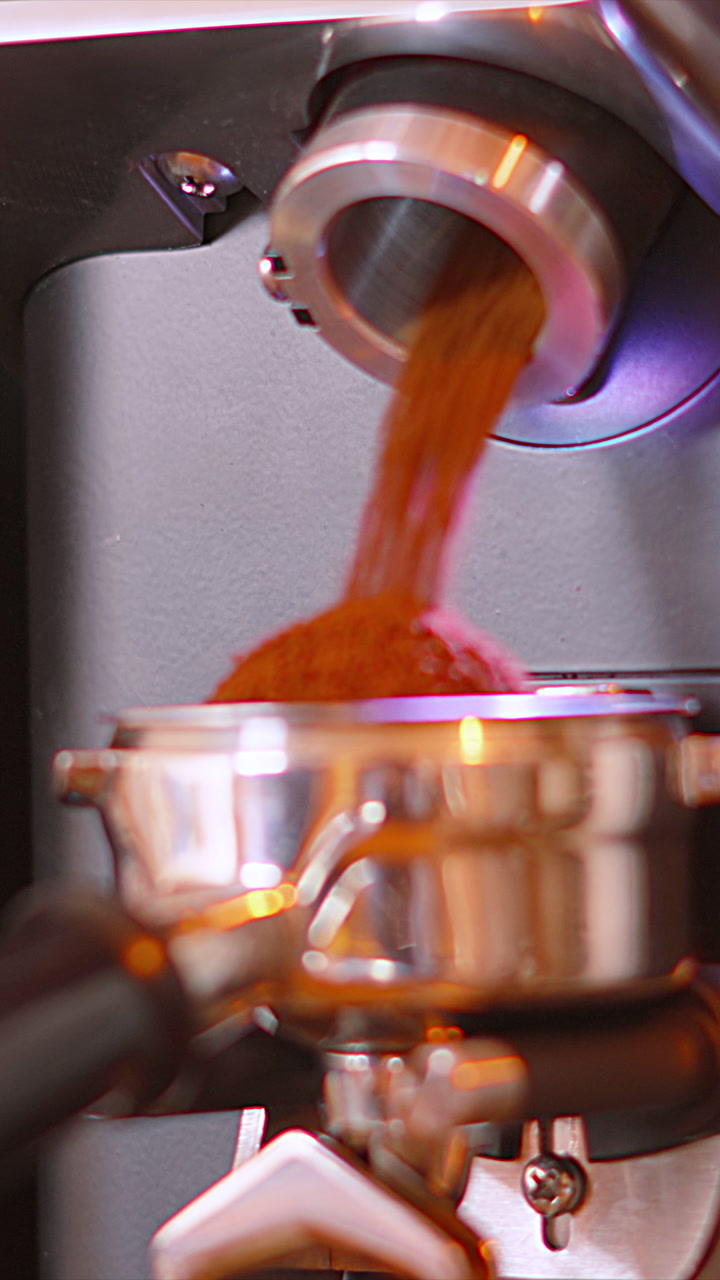 Vertical Video of Coffee Grinder Machine Shooting Out Granules into Portafilter. Independent Local Cafe Business Shop Clip. Making Hot Beverage. 9:16 Reels Shorts Format.