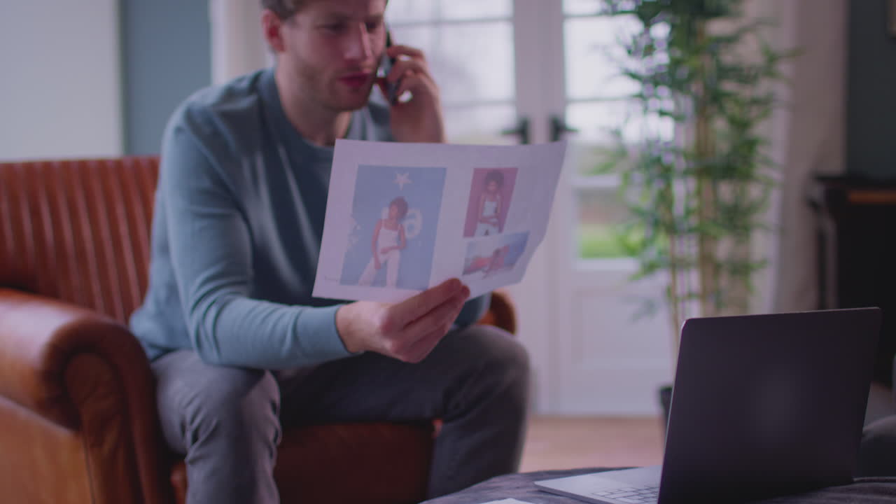 Man Working From Home In Creative Design Or Marketing Industry On Phone Approving Artwork Design