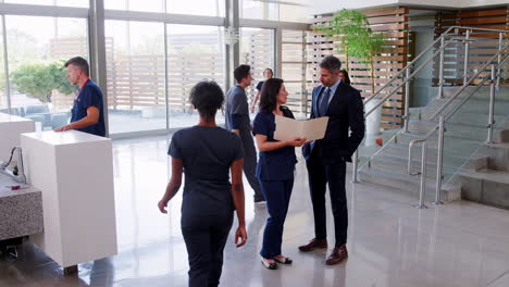 Male-doctor-and-female-nurse-talking-in-a-hospital-lobby