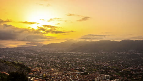 toma en ángulo alto de la ciudad de palermo en sicilia, italia en primer plano y cordillera en el fondo con puesta de sol sobre el horizonte