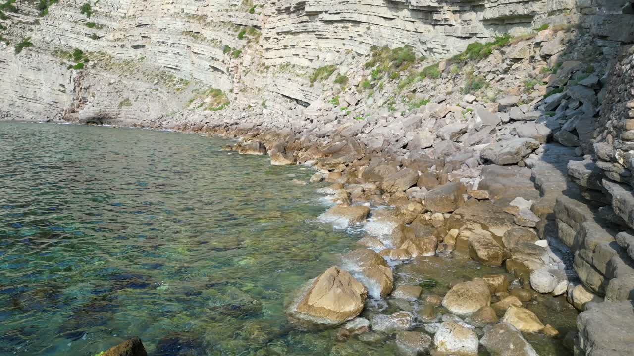 Transparent turquoise water flows between rocks in a bay in Ibiza, Spain. Fabulous aerial view flight overflight flyover drone