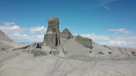 Aerial-View-of-ATV-Quad-Moving-Under-Sandstone-Rock-Formation-Near-Factory-Butte-in-Utah-Desert-USA