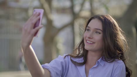 Woman-having-video-chat-on-phone-in-park,-showing-surroundings