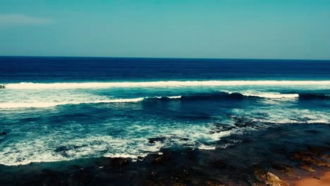 Aerial-footage-filmed-with-a-drone-overlooking-the-beach-and-sea-of-crashing-waves-with-a-deep-blue-ocean-on-the-Bluff-in-Africa-southern-hemisphere