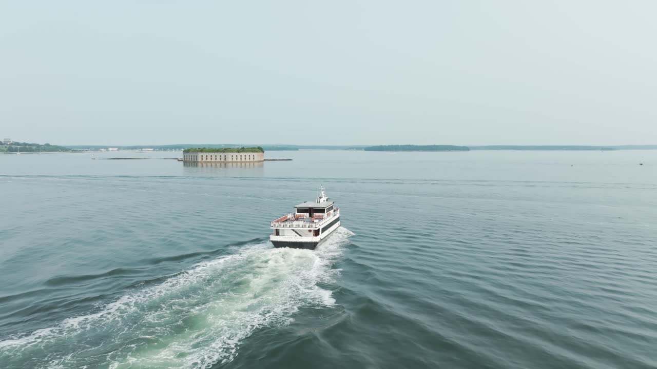 Tour boats cruise through Casco Bay in Portland, Maine with Fort Gorges in the distance—serene summer day on the Atlantic.