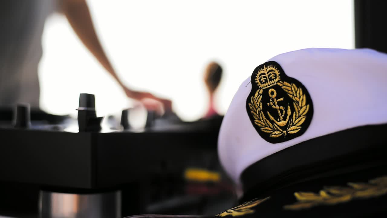 Dj playing music on yacht party with professional mixer and turntable next to a navy navy sailor captain hat