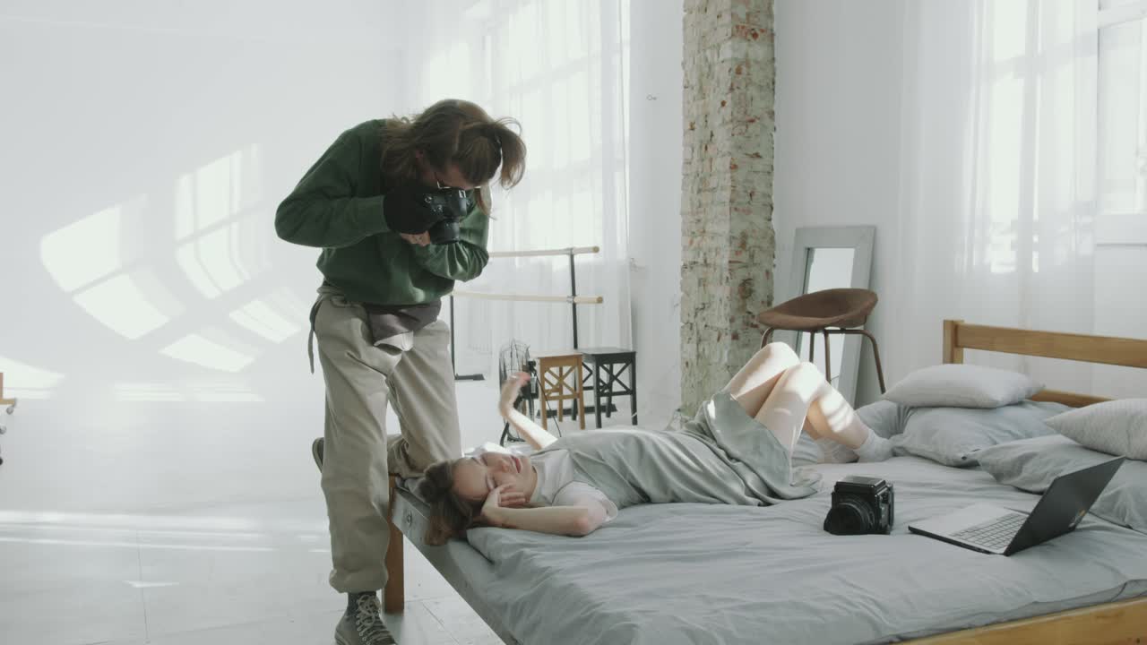 Photographer Taking Pictures of Woman Lying on Bed in Minimalist Studio