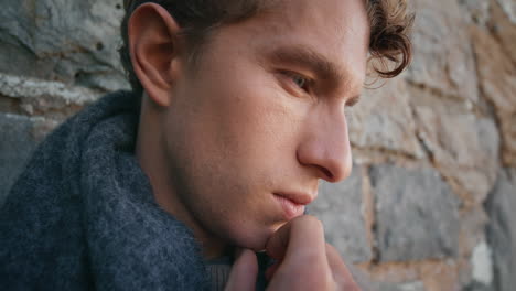 thoughtful man looking distance standing in front stoned wall alone closeup