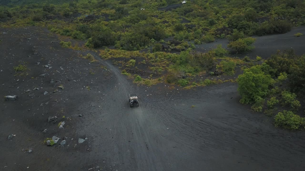 aviones no tripulados que vuelan hacia los autos que conducen fuera de la carretera sobre arena volcánica en un bosque, volcán pacaya, guatemala, centroamérica