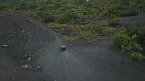 Aviones-No-Tripulados-Que-Vuelan-Hacia-Los-Autos-Que-Conducen-Fuera-De-La-Carretera-Sobre-Arena-Volcánica-En-Un-Bosque,-Volcán-Pacaya,-Guatemala,-Centroamérica