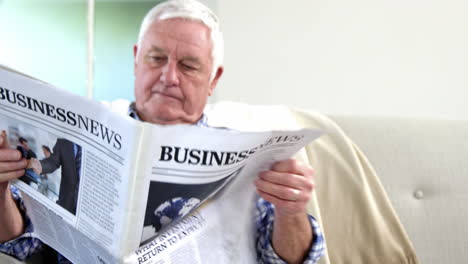 senior man reading newspaper on couch