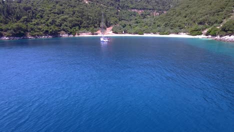 Foki-Strand-Auf-Kefalonia-Mit-Türkisfarbenem-Wasser-Und-Einer-Einzigen-Yacht,-Luftaufnahme