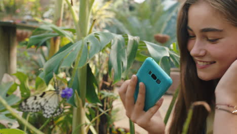 niña de la naturaleza tomando una foto de una mariposa usando un teléfono inteligente en un santuario de vida silvestre aprendiendo el hábitat natural disfrutando de una excursión al zoológico compartiendo la conciencia ambiental en las redes sociales 4k