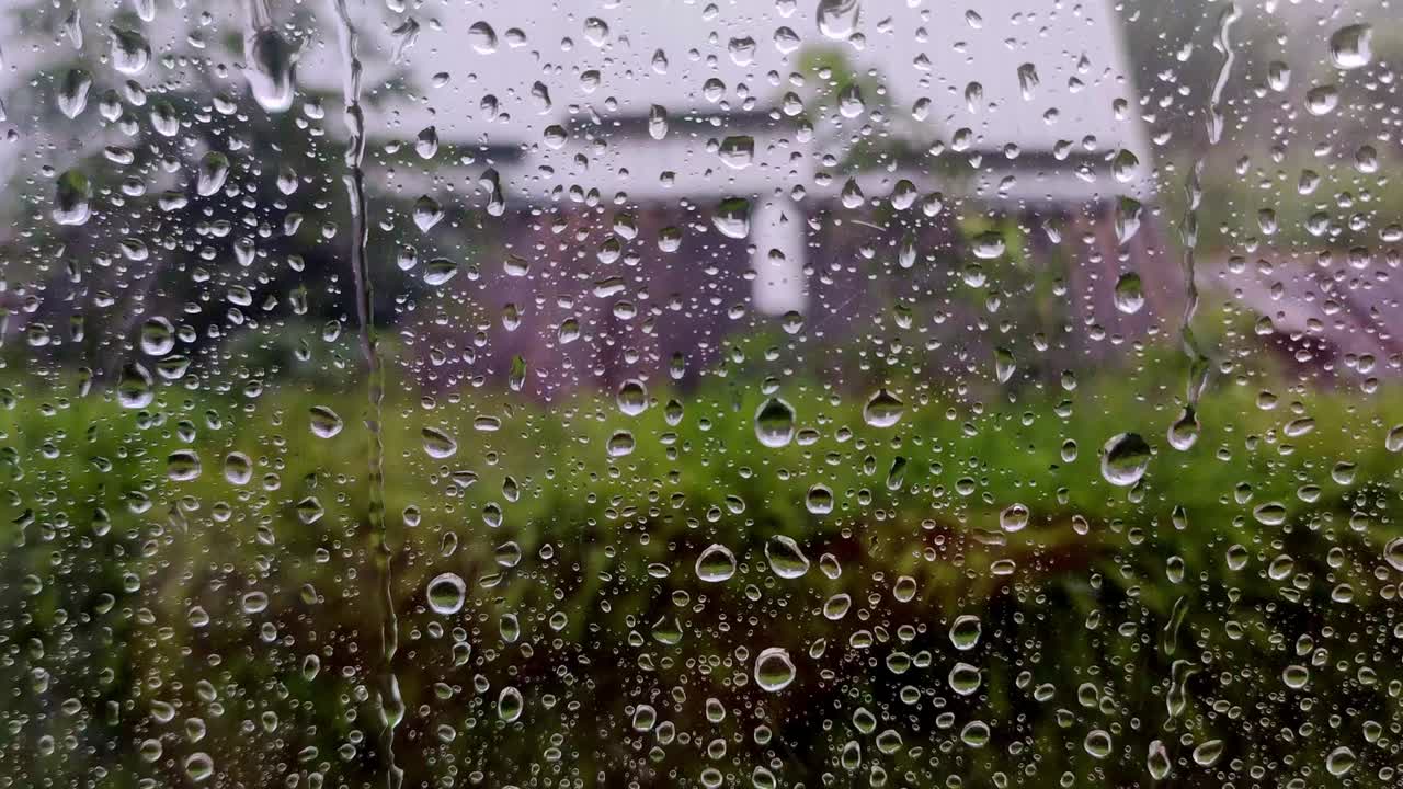 Real rain drops sliding on home window glass. Heavy rain. Close-up of water droplets on glass.