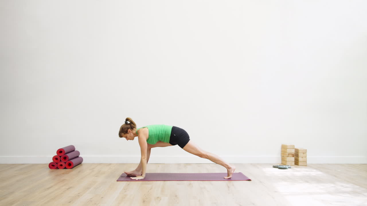 Mulher praticando posturas de yoga em um tapete em um estúdio iluminado.