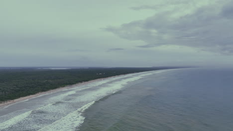 Vuelo-Aéreo-A-Través-Del-Mar-Desde-La-Larga-Curva-De-Rainbow-Beach-Y-El-Interior-Boscoso