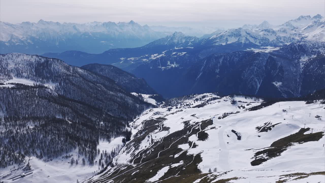 Snow-covered slopes and vast mountain ranges near Cheneil, Aosta Valley, overcast sky, dramatic winter scenery, ideal for nature, travel, alpine themes. Italy. Aerial drone