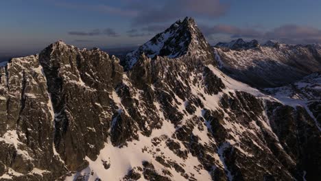 Wild-rugged-rocky-and-snowy-mountains-on-beautiful-day-as-the-sun-is-setting-with-blue-skies-and-rolling-clouds