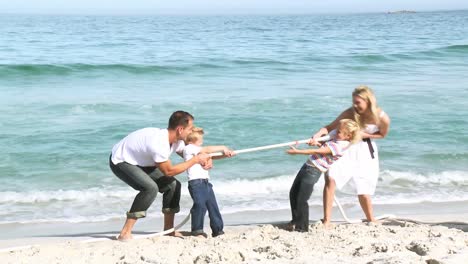 parents and children playing with a string on the beach