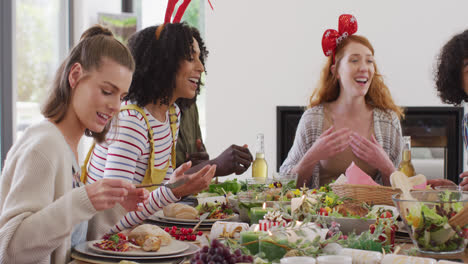 happy group of diverse friends sitting at table and eating dinner together