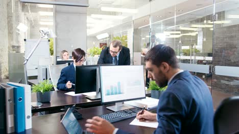 un equipo diverso de hombres y mujeres de negocios que trabajan en sus escritorios en la oficina moderna. tienen discusiones, trabajan con papeles y hacen negocios profesionalmente.