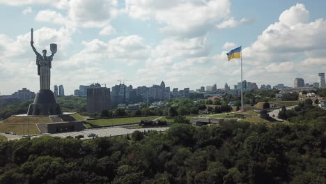 4k-Luftaufnahmen-Des-Mutterlanddenkmals-Und-Der-Ewigen-Flamme-Mit-Riesiger-Ukrainischer-Flagge-An-Einem-Bewölkten-Sommertag