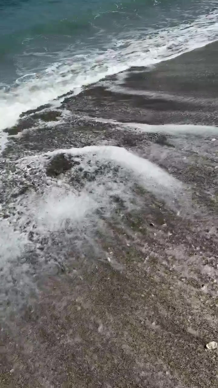 Onde dell'oceano che si infrangono su una spiaggia di sabbia scura