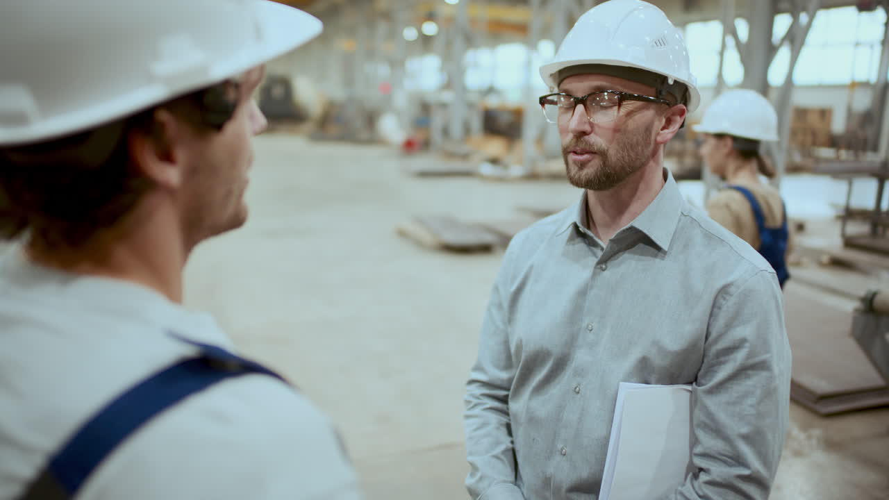 ingeniero de la fábrica saludando al trabajador con un apretón de mano y hablando con él