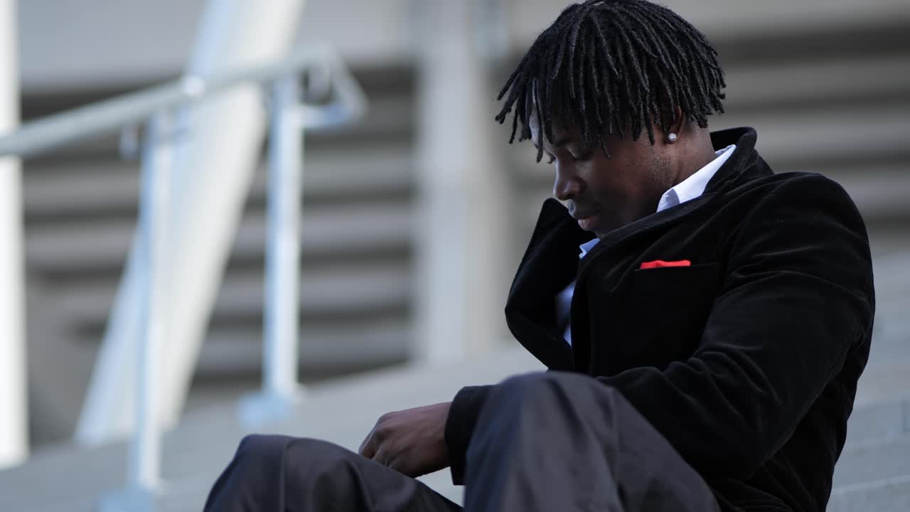 Close-up of a young African businessman texting while sitting on a staircase