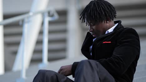 close-up of a young african businessman texting while sitting on a staircase