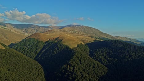 push in aerial drone shot with tarcului mountains on a sunny day with blue skies