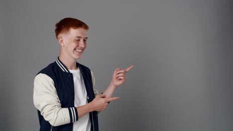 redhead boy looking at camera and pointing on copy space.