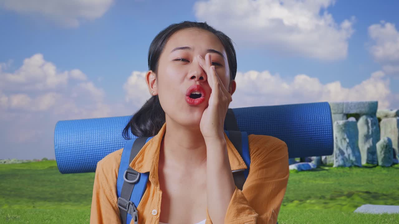 Close Up Of Asian Female Hiker With Mountaineering Backpack Screaming Holding Hands Near Her Mouth While Traveling In Stonehenge