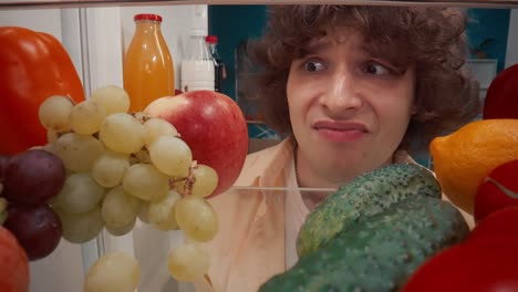 confused person looking inside a refrigerator filled with food