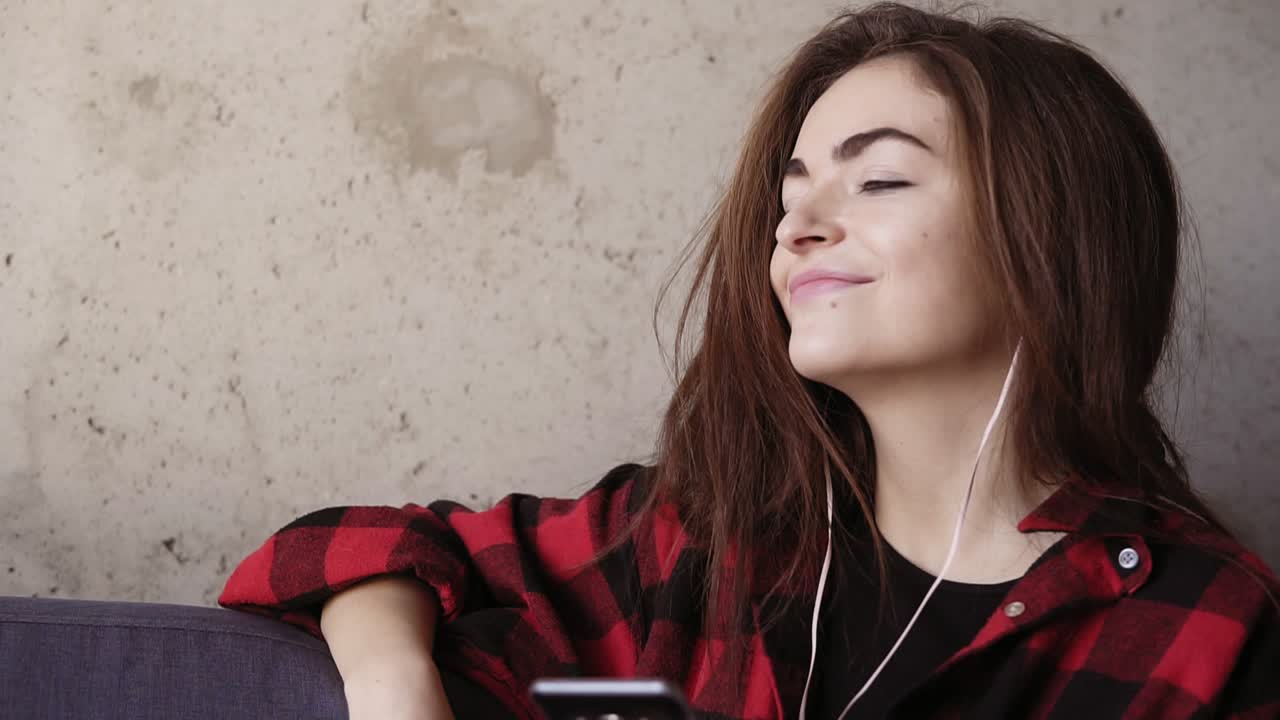 Young beautiful brunette girl in her 20's enjoys listening and dancing to the music in her headphones.