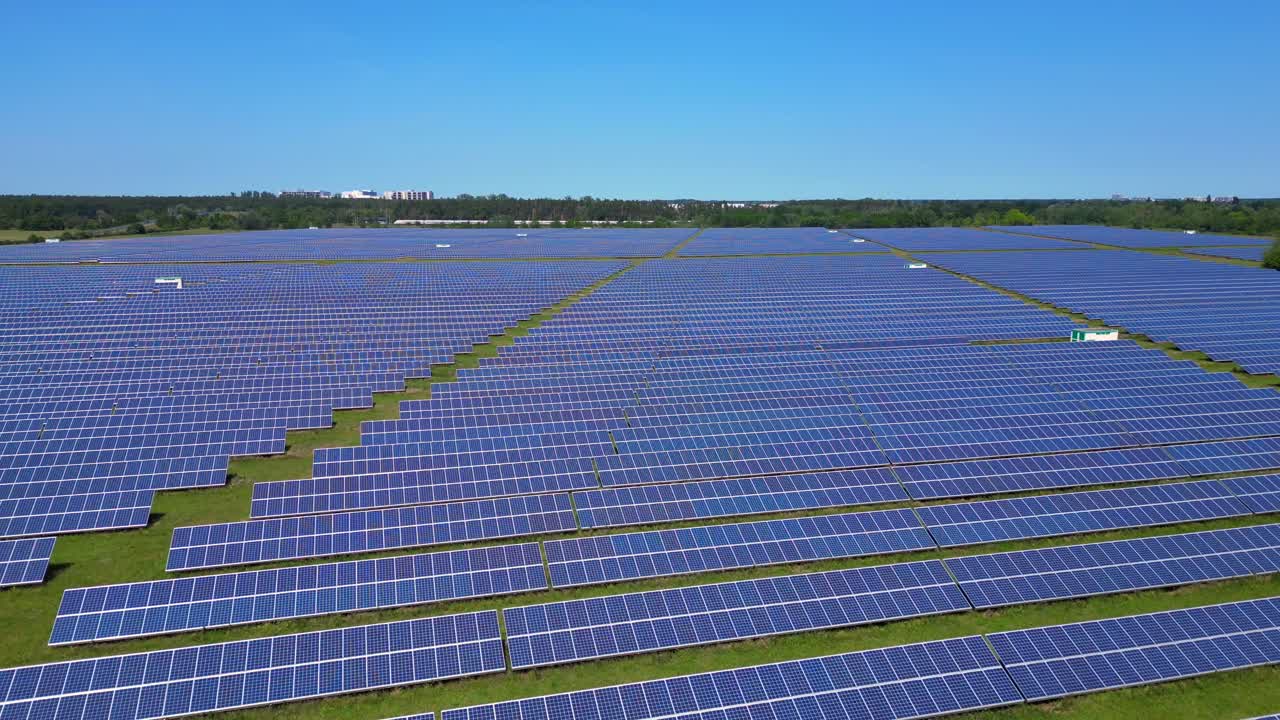Rækker af fotovoltaiske solpaneler absorberer solen i et stort kraftværk under en klar blå himmel. Magisk luftfoto, panoramaoversigt fra drone