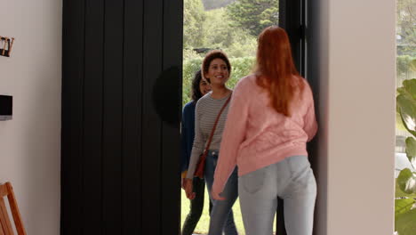 female friends hugging and greeting each other at home, smiling and happy