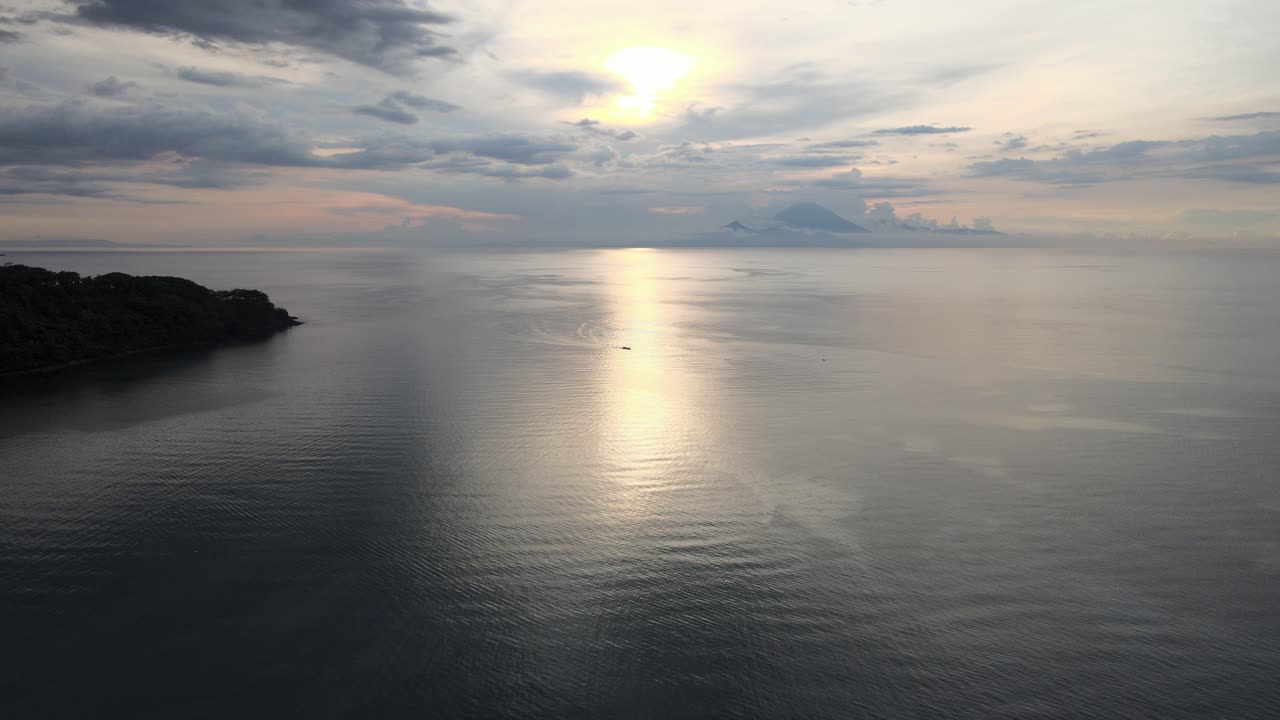 Vista aerea di un oceano calmo al tramonto con un'isola in lontananza