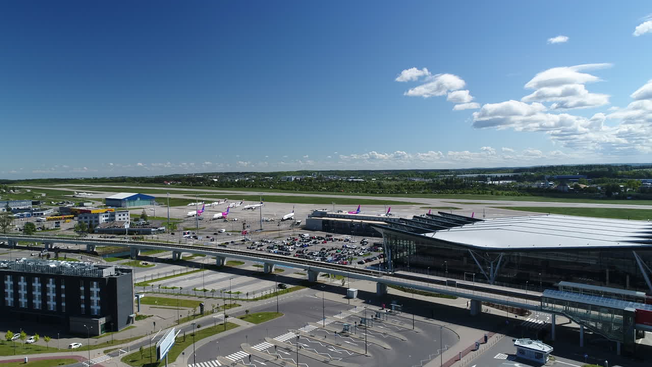 Drone shot of a terminal at Gdansk airport (GDN) in Poland. Aerial view of beautiful Pomorska Kolej Metropolitalna railway tracks near airport. Commercial airplanes at airport.