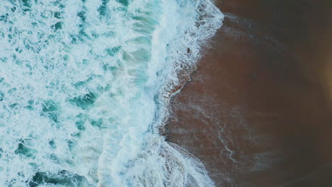 ocean waves meeting beach making foam aerial view. sea water crashing seashore