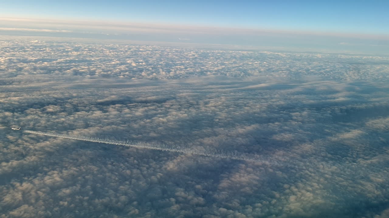 vista increíble desde la cabina de un avión que vuela alto por encima de las nubes dejando un largo rastro de aire de vapor de condensación blanco en el cielo azul