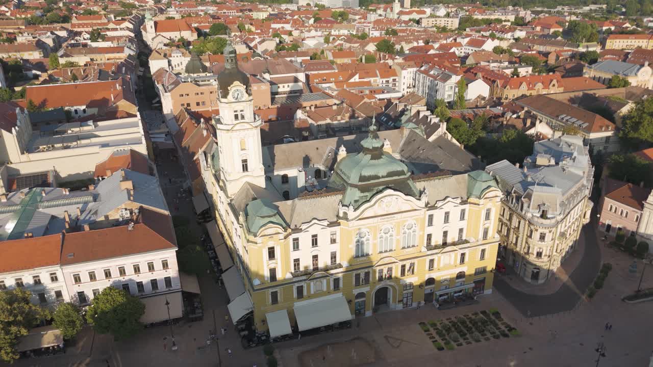 Dron krouží kolem věže radnice v Pécsi s městskou scenérií v pozadí