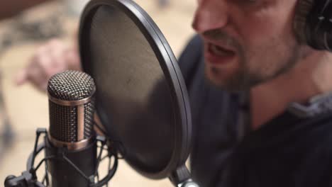 pop filter and condenser mic with singing singer, high angle closeup