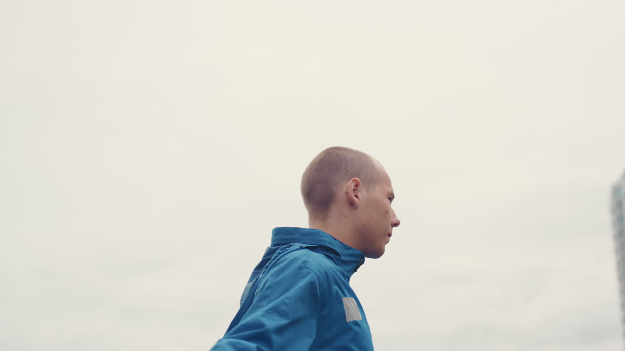 white athlete on city rooftop surveying skyline and preparing for training, profile shots capture calm determination, steady posture, breath control and poised movement against overcast building