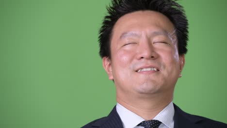 hombre de negocios japonés maduro contra un fondo verde